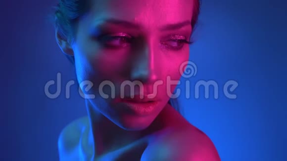 特写镜头在模特的轮廓与闪光的化妆蓝色和粉红色的霓虹灯在肩膀上观看镜头视频的预览图