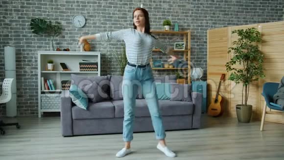 快乐的年轻女士在家跳舞移动身体享受音乐和活动视频的预览图