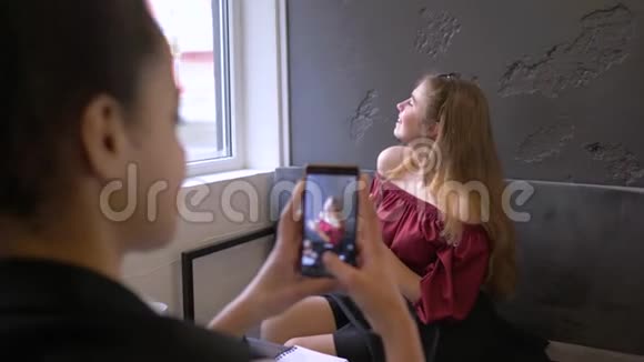 快乐的多民族朋友年轻的黑皮肤女人用手机拍女朋友手里拿着一杯茶视频的预览图