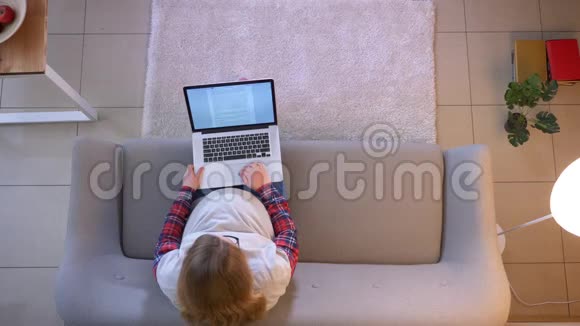 年轻孕妇坐在室内沙发上用笔记本电脑拍摄特写镜头视频的预览图