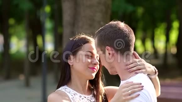 一对相爱的夫妇在一个夏天公园的绿树背景上的肖像视频的预览图