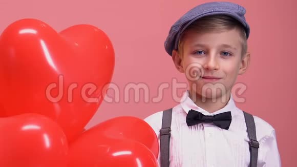 害羞的小男孩带着心形气球对着相机微笑情人节礼物视频的预览图