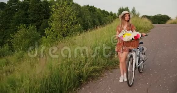 一个漂亮的女人戴着帽子骑着自行车穿着轻盈的夏装带着花篮微笑着视频的预览图