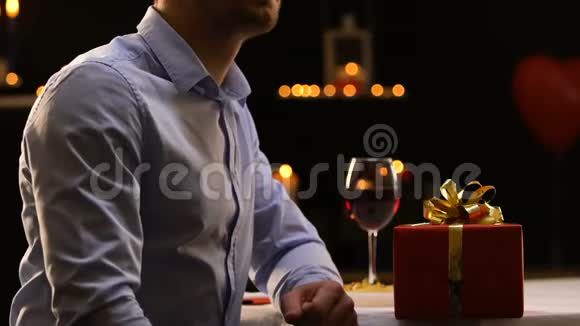 沮丧的男朋友把礼物放在桌子上离开餐馆分手视频的预览图