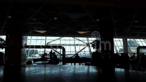 机场候机楼咖啡馆的人剪影有全景窗视频的预览图