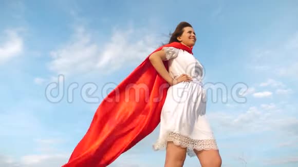 美丽的女孩梦想成为超级英雄性感的超级英雄女孩穿着红色斗篷站在田野上斗篷飘扬着视频的预览图