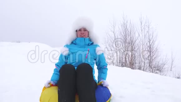 快乐的女孩骑着雪碟笑女人在冬天雪橇微笑着山区度假胜地圣诞节假期视频的预览图