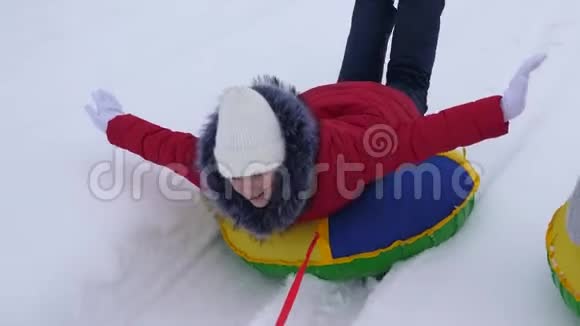 在冬天少女们在雪白色的道路上乘雪橇女朋友在雪地里骑雪碟圣诞节假期视频的预览图