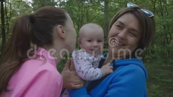 森林里幸福的家庭母亲亲吻她的孩子和幸福的祖母视频的预览图