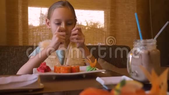快乐少女在亚洲餐厅吃寿司卷时用筷子劈叉视频的预览图