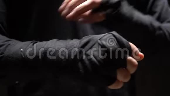 男性手缠上一条黑色弹力绷带黑色背景视频的预览图