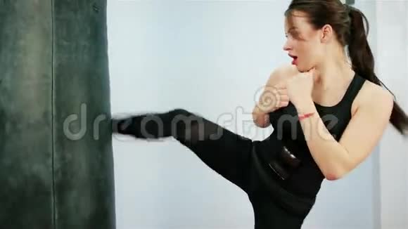 美丽的黑发拳击梨美丽的跆拳道女子训练袋在健身室激烈的力量适合视频的预览图