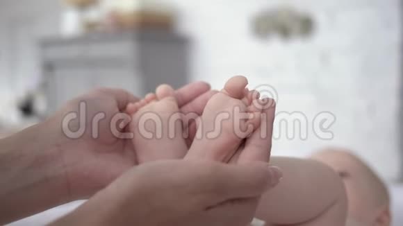 作为母亲母亲关心的手臂托着刚出生的小女孩的小脚视频的预览图