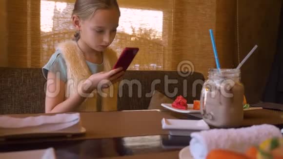 日本咖啡馆中使用智能手机拍摄寿司卷的少女视频的预览图