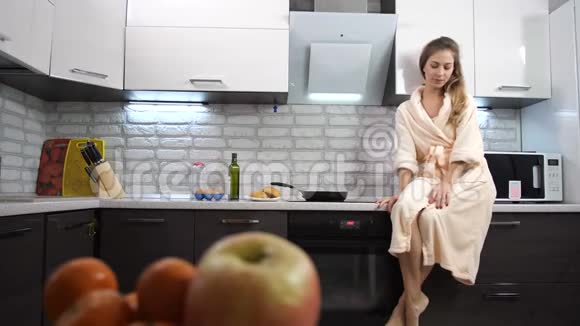 女孩吃了一个面包做了一个脸吐在垃圾桶里厨房里穿浴袍的女孩4K慢慢视频的预览图