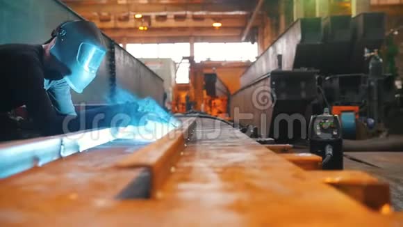 一个戴着防护面具的男人坐在一根铁梁上靠焊接工作焊接板在它的右边视频的预览图