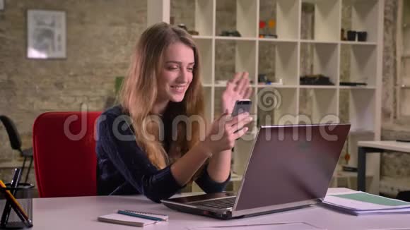 办公室里一位金发碧眼的白人女商人在笔记本电脑前愉快地用视频聊天视频的预览图