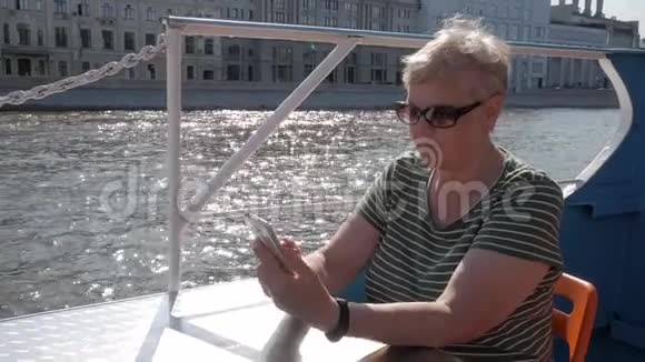 成年妇女坐在旅游船上手持智能手机视频的预览图