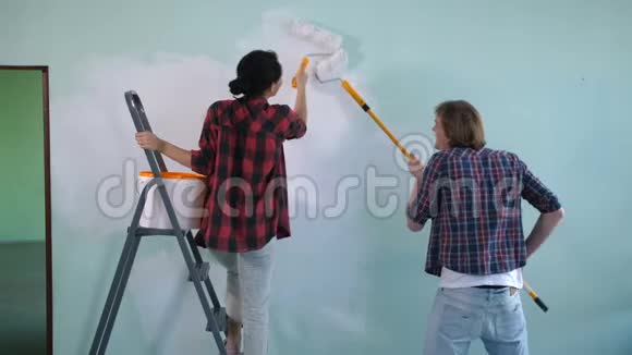 新婚夫妇在新房子里粉刷内墙视频的预览图