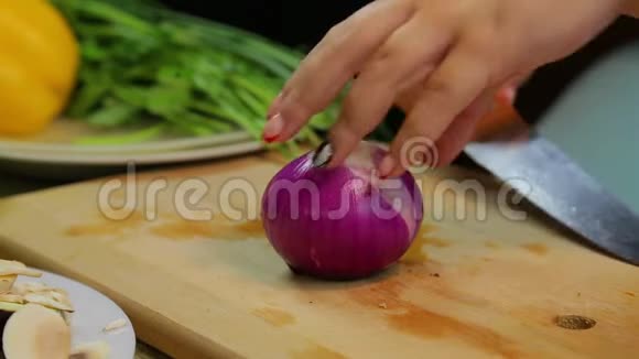 一个女人用刀子在木板上切一个红色的洋葱视频的预览图