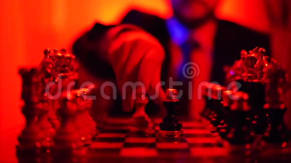 一个穿着西装的商人坐在模糊的背景下在明亮的红灯背景下孤立无援地下棋视频的预览图