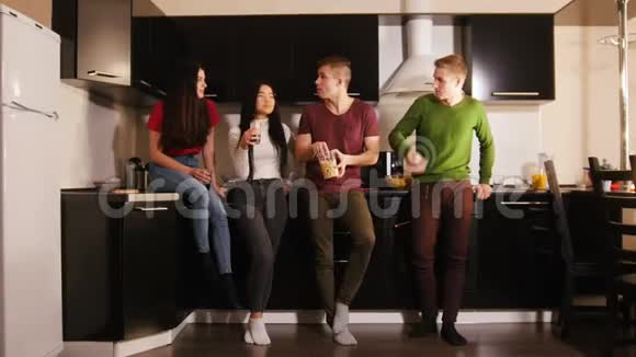 一群年轻有魅力的朋友一起站在厨房里会说话会笑会吃零食视频的预览图