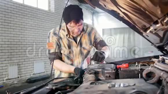 汽车服务机械师在引擎盖下拔掉汽车的一部分视频的预览图