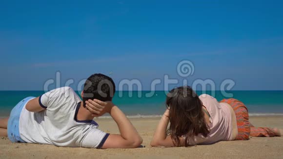 躺在美丽海滩上看着飞机降落的年轻男女视频的预览图