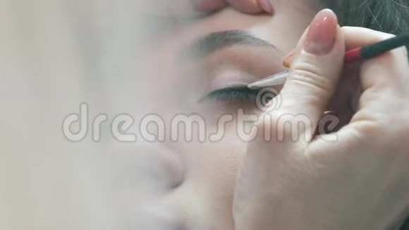 化妆师之手的特写在眼睛上涂抹阴影视频的预览图