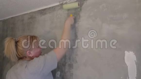 一个女人用滚筒在粉刷墙壁之前对墙壁进行处理视频的预览图