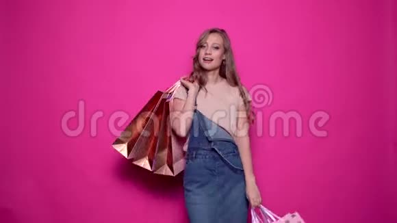 穿着牛仔服装摆着五颜六色购物袋的年轻女人视频的预览图