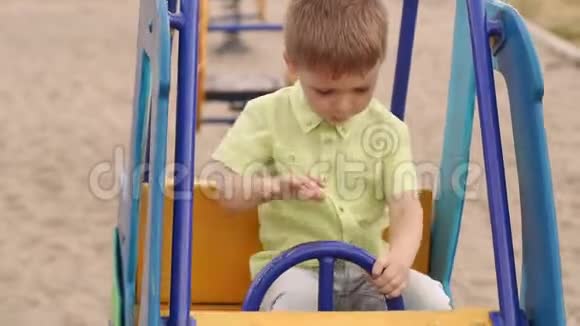 那个孩子坐在操场上一辆儿童车的车轮前视频的预览图