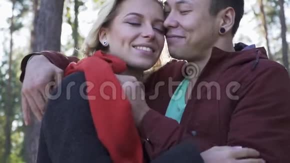 年轻的微笑情侣相爱在松树和夕阳的背景下接吻快乐的家庭在户外视频的预览图