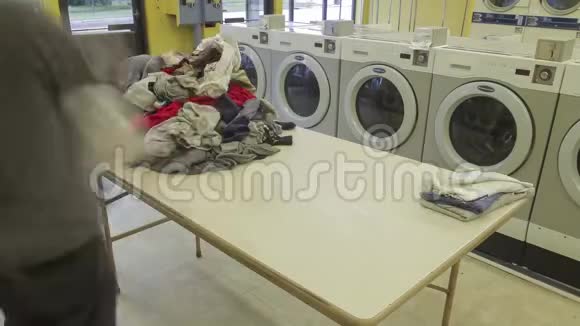 一个人在洗衣店4KUHD时间段折叠和整理干净的洗衣房的大角度镜头视频的预览图