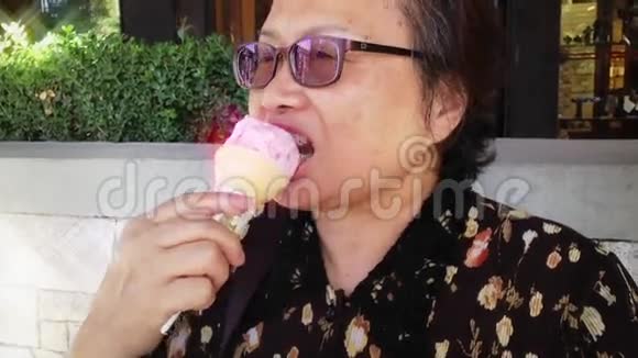 快乐的老妇人在公园吃草莓冰淇淋视频的预览图