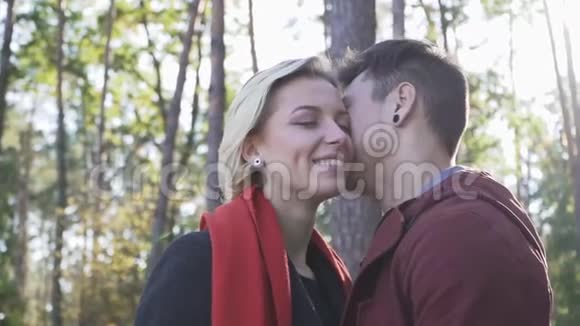 年轻的微笑情侣相爱在松树和夕阳的背景下接吻多民族情侣相爱视频的预览图