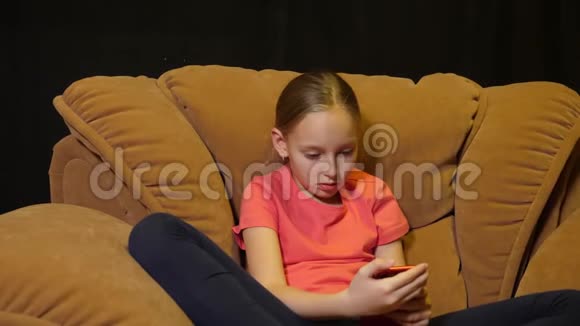 在家庭客厅舒适的椅子上使用智能手机放松的青少年女孩视频的预览图