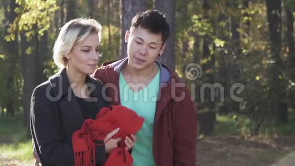 一对年轻的多民族夫妇穿着休闲服装在阳光的背景下穿过森林恋爱中的情侣视频的预览图