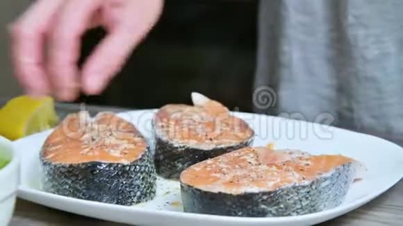 一个烹饪女孩的手的特写她准备新鲜的鱼鲑鱼鳟鱼用柠檬汁浇水挤压柠檬视频的预览图
