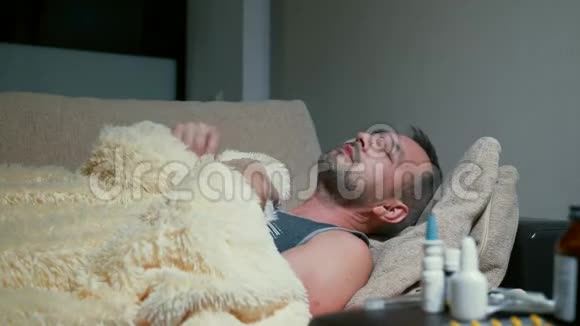 病人躺在沙发上用毯子盖着自己用温度计测量体温视频的预览图
