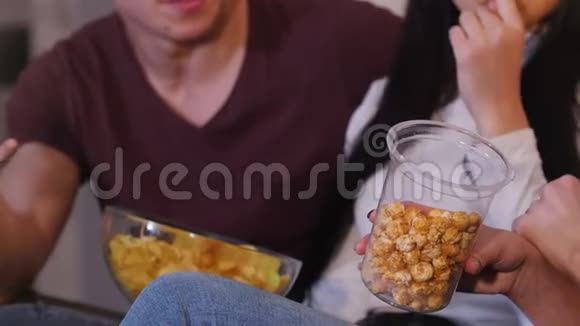 一群年轻的朋友在一起坐在沙发上看电视聊天吃垃圾食品视频的预览图