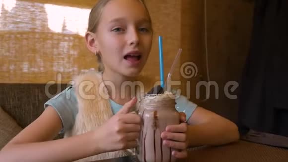 肖像少女在咖啡馆的餐桌上喝着奶昔鸡尾酒视频的预览图