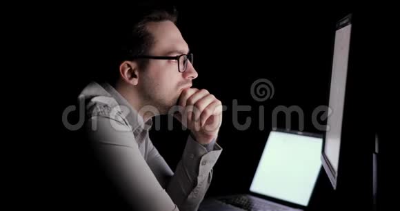 人类在电脑上工作在黑暗中在工作场所仔细阅读文件视频的预览图