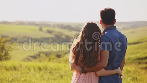 年轻夫妇站在夕阳下的大自然中望着远处的某个地方指着它视频的预览图