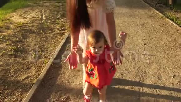 妈妈抓住了在公园里学会走路和微笑的小宝宝慢动作视频的预览图
