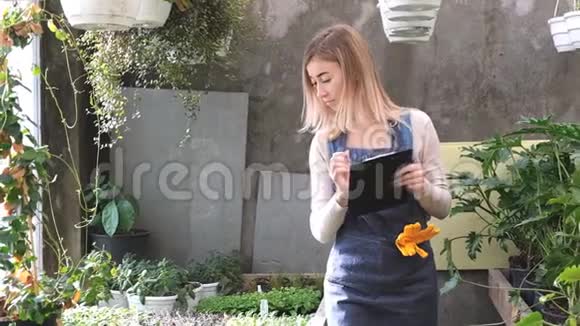 一位年轻的女园丁在温室里保存着花的记录视频的预览图