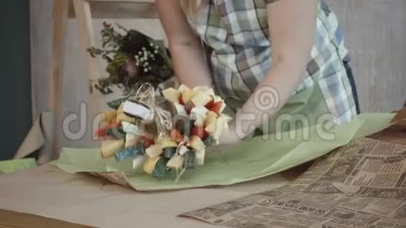 用牛皮纸包裹可食用花束的女性手视频的预览图