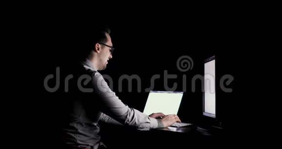 程序员在办公室加班深夜坐在两台显示器前用键盘打字视频的预览图