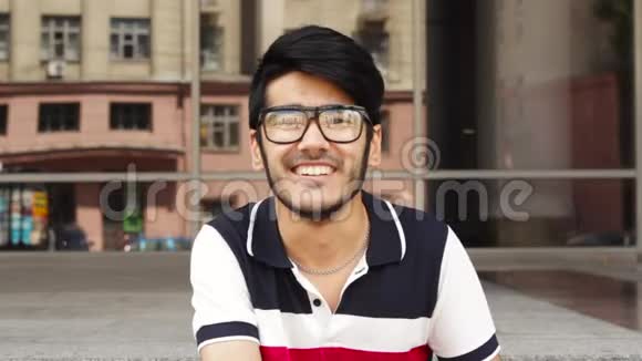 戴眼镜的快乐亚洲男人微笑着相机视频的预览图