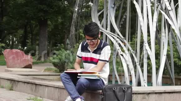 坐在喷泉附近学习的男学生视频的预览图